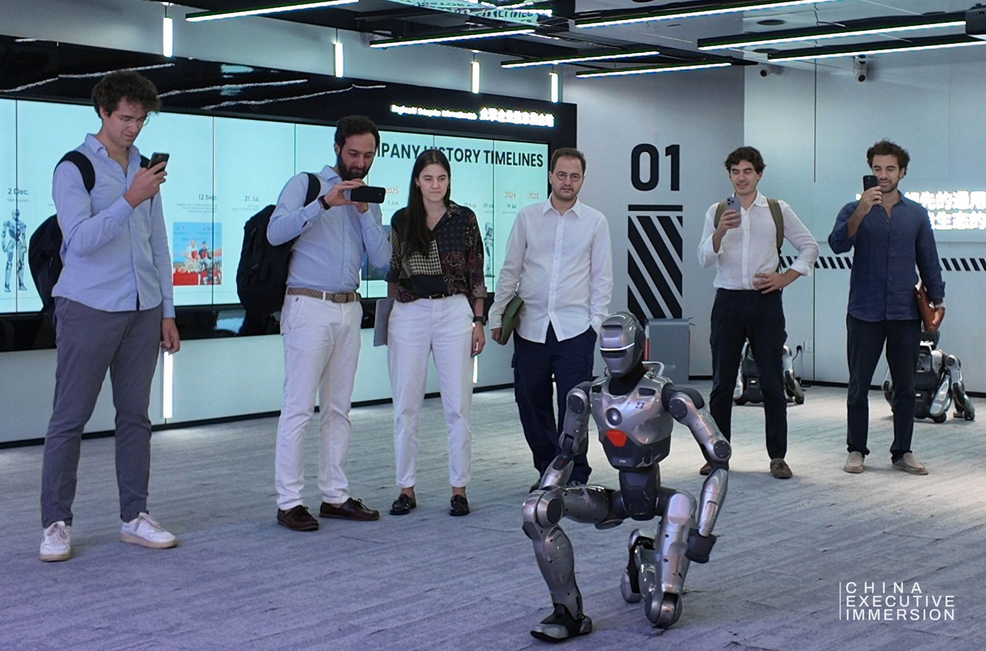 Humanoid demonstration — a humanoid walking the floor a metre from the group — Shenzhen